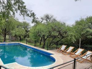 a swimming pool with lounge chairs and a fence at Indigo CCH in Carpintería