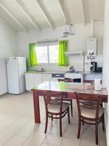 a kitchen with a table and two chairs and a kitchen with yellow curtains at Apart Jazmines del Río in Santa Rosa de Calamuchita