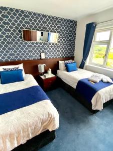 1 dormitorio con 2 camas y espejo en la pared en Cullentra House en Cushendall