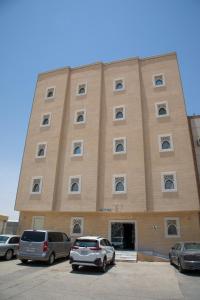 un gran edificio con coches estacionados en un estacionamiento en صالة وغرفتين نوم دخـول ذاتي, en Al Kharj