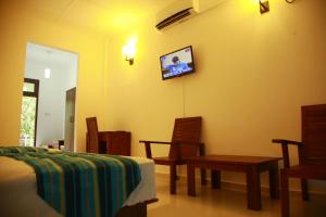 a bedroom with a bed and a tv on the wall at Samwill Holiday Resort in Kataragama