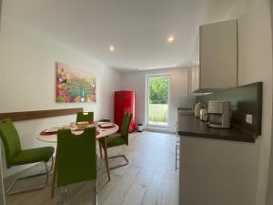 a kitchen and dining room with a table and green chairs at Fischbach Apartment in Saarbrücken