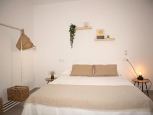 een witte slaapkamer met een bed en 2 tafels bij Villa Alegría in Chiclana de la Frontera