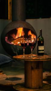 two glasses of wine on a table next to a fireplace at Skyline Ecoliving Santa Elena in Santa Elena