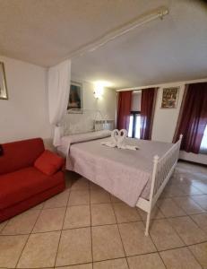 1 dormitorio con cama blanca y sofá rojo en Monolocale in via pedonale, en Saint Vincent
