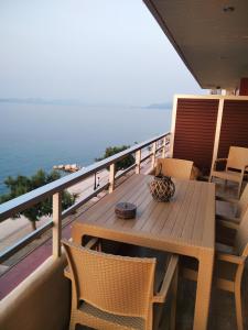 SKY AND SEA APARTMENT في غزيلوكاسترون: طاولة وكراسي خشبية على شرفة مع المحيط