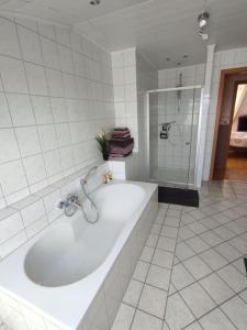 La salle de bains blanche est pourvue d'une baignoire et d'une douche. dans l'établissement Ferienwohnung im Grünen, à Geldern