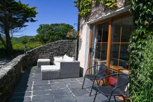a patio with a couch and chairs on a stone wall at The Olde Forge B & B in Caherdaniel