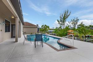 un patio con mesa y sillas junto a una piscina en Gulf Access, Heated Pool, Sleeps 6 - Villa Peaceful Palms - Roelens Vacations, en Cabo Coral