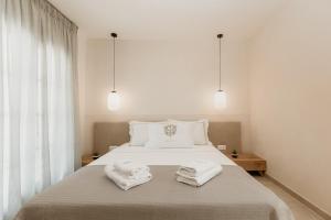 a bedroom with a white bed with towels on it at TRINITY THE HOTEL in Ammouliani