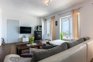 een woonkamer met een bank en een tv bij Apartments Chiara mit Meerblick und Pool in Lovran