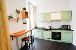 a small kitchen with green cabinets and a counter at Une Pause quelque part in Marseille