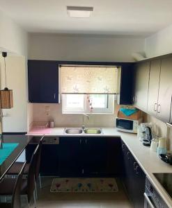 uma cozinha com armários azuis, um lavatório e uma janela em Sweet Makri Suite em Nea Makri