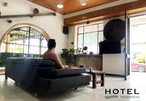 a man sitting on a couch in a living room at El Hotel Tisquesusa in Girardot
