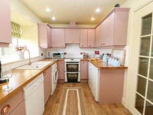 eine Küche mit rosa Schränken und einem Waschbecken in der Unterkunft The Granary in Morpeth