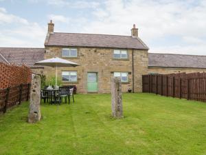 a house with a yard with a table and an umbrella at The Granary in Morpeth