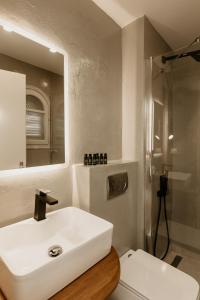 bagno con lavandino bianco e specchio di TRINITY THE HOTEL ad Ammouliani