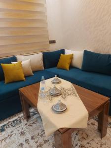 a living room with a blue couch and a table at L'horizon Aéroport Appartement in Marrakech