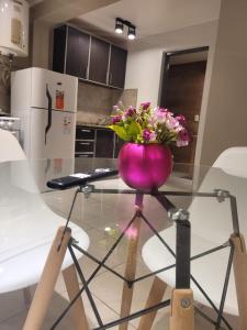 a purple vase with flowers on a glass table in a kitchen at Zona Alta in San Fernando del Valle de Catamarca