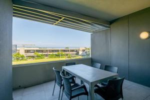 a room with a table and chairs and a large window at Pebblebeach 2 bedroom Apartment in Sibaya