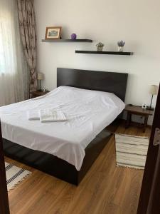 a bed with a black frame and white sheets at Alex Apartament in Mangalia