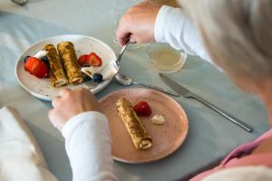 Eine Frau, die an einem Tisch mit einem Teller Essen sitzt. in der Unterkunft B&B Kraneveld in Haacht