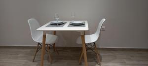 een witte tafel met drie stoelen en wijnglazen erop bij 2downtown.skg in Thessaloniki +39 foto's
