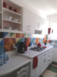 a kitchen with white cabinets and colorful tiles on the wall at Departamento Mariposas in Oaxaca City