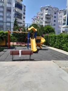 Denize Yakın Daire في أنطاليا: حديقة بها ملعب مع زحليقة ومقعد