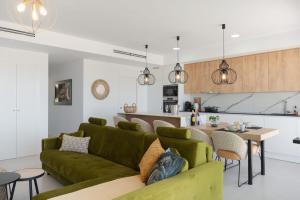 een woonkamer met een groene bank en een keuken bij Ap Camporrosso Stone Valley 1B by Bookaparadise in Finestrat