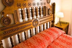 a bed with a wooden headboard with a red pillow at Hospedaje Octavio in Santillana del Mar