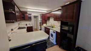 une cuisine avec des placards en bois et un comptoir blanc dans l'établissement Rooms Shared Kitchen FREE Parking, à Slough