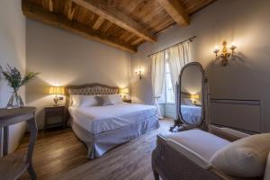 een slaapkamer met 2 bedden, een spiegel en een bank bij Tenuta Bussia - Wine Relais & Spa in Monforte dʼAlba