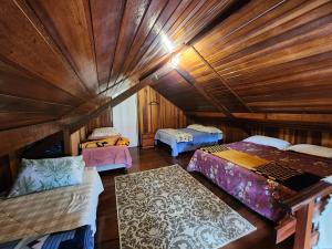 a room with three beds in a wooden cabin at A casa Girassol in Campos do Jordão