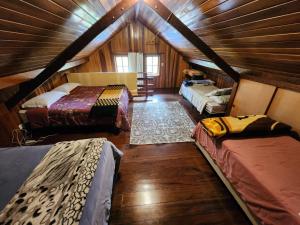 Habitación con 3 camas en una casa de madera en A casa Girassol, en Campos do Jordão