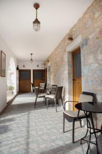 ein Zimmer mit Stühlen, Tischen und einer Steinmauer in der Unterkunft TRADITIONAL HOUSE ALEPIS IN AREOPOLIS in Areopoli
