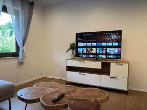 sala de estar con TV de pantalla plana y 2 mesas en Ferienhaus am blauen Wasser, en Essing