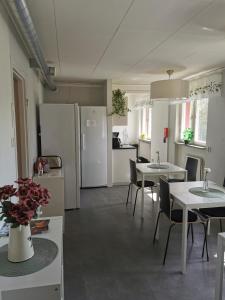 uma cozinha com electrodomésticos brancos, mesas e cadeiras em Saxvikens vandrarhem em Mora