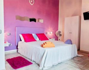 a pink bedroom with a white bed with pink walls at Sa Pramma in Baratili San Pietro
