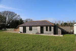 an old house in a field next to a yard at Fletchers Bothy in Bosham
