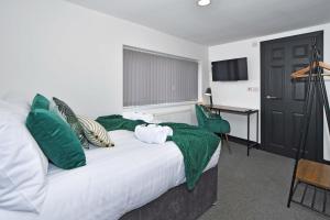 sypialnia z łóżkiem z zielonymi poduszkami i biurkiem w obiekcie Adventure Place by YourStays w mieście Stoke-on-Trent