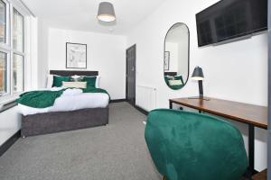 1 dormitorio con cama, escritorio y silla verde en Adventure Place by YourStays en Stoke on Trent