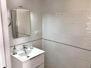 La salle de bains blanche est pourvue d'un lavabo et d'un miroir. dans l'établissement Casa Iris, à Conil de la Frontera