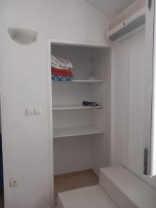 einen begehbaren Kleiderschrank mit weißen Wänden und Regalen in der Unterkunft Studio Apartment Bosko in Novalja