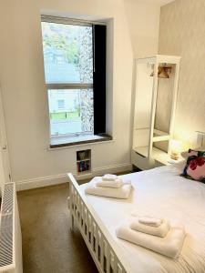 una camera da letto con un grande letto bianco con asciugamani di Bellaview Apartment Barmouth a Barmouth