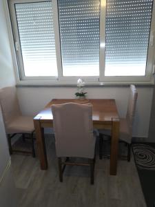 a dining room table with two chairs and two windows at Apartmens Zora in Tribunj
