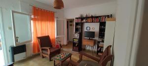 uma sala de estar com um sofá, uma televisão e uma cadeira em Habitación Privada en casa compartida para viajeros em Córdoba