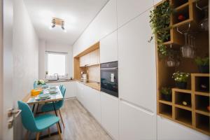 eine Küche mit weißen Schränken und einem Tisch und Stühlen in der Unterkunft Creamy Wood Haven in Oradea
