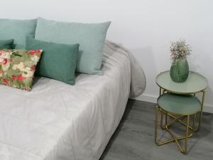 einem Bett mit Kissen und einem Tisch mit Vase darauf in der Unterkunft Alojamento familia Carvalhais in Ponte de Vagos