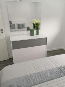 ein weißes Schlafzimmer mit einem Bett mit Blumen im Spiegel in der Unterkunft Alojamento familia Carvalhais in Ponte de Vagos